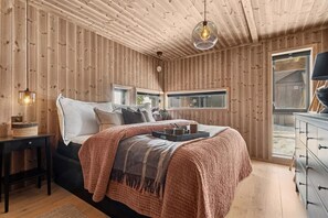 A wooden-paneled bedroom with a bed, bedside table, and a window.