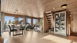 A spacious living area with a dining table, sofas, and a staircase.
