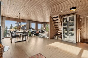 A spacious living area with a dining table, sofas, and a staircase.