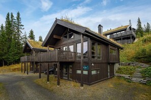 Eine Holzhütte mit Balkon, großen Fenstern und einem Schild, das anzeigt, dass es sich um ein Salu handelt.