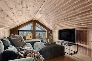 Ein gemütliches Loft-Zimmer mit großem Fenster, Flachbildfernseher und einer bequemen Sitzecke.