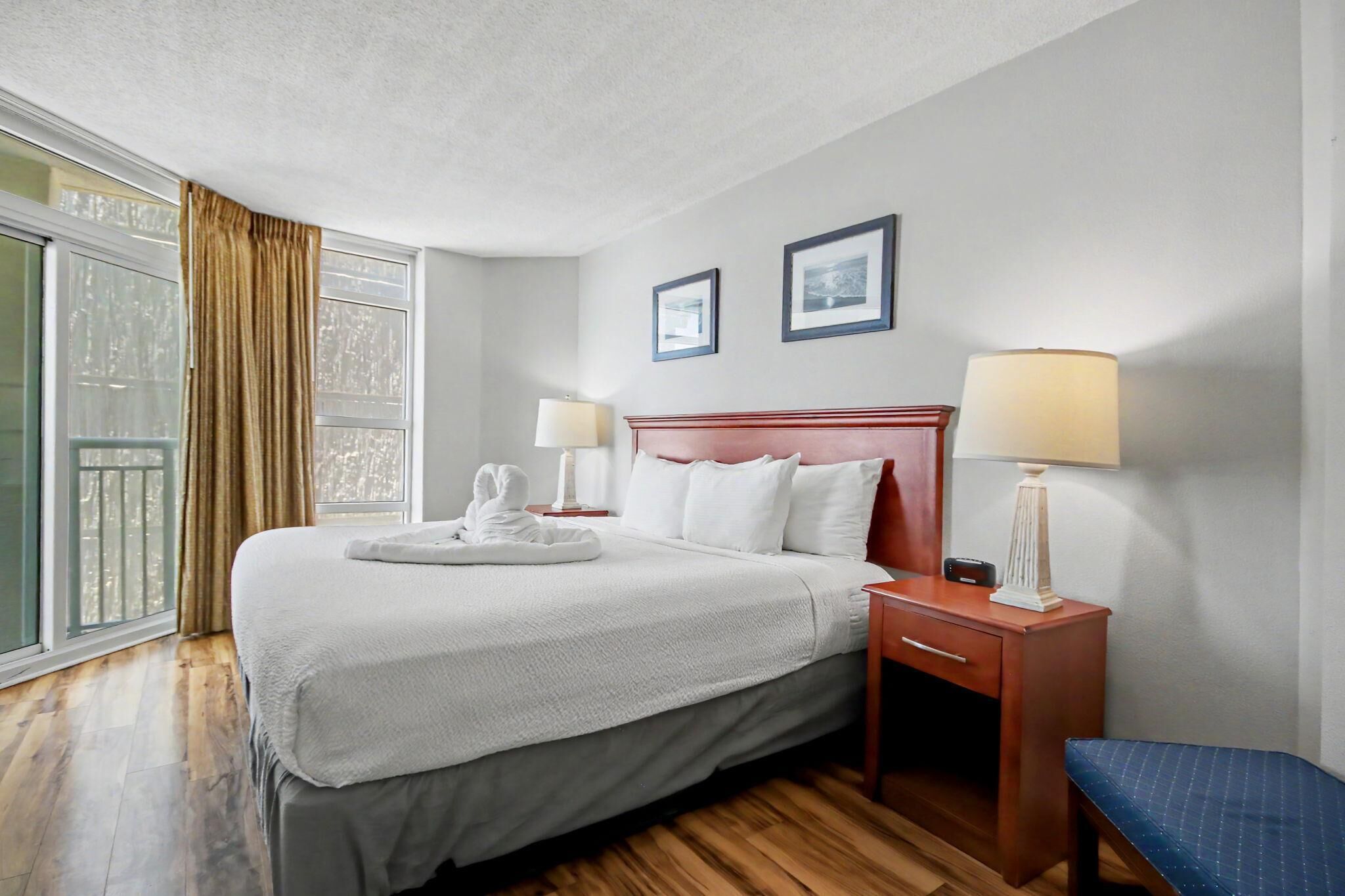Une chambre d’hôtel avec un lit, des lampes de chevet, une table de chevet, une chaise et une fenêtre avec des rideaux.