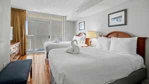 Habitació d'hotel amb dos llits, un panell de capçalera de fusta, una panxa, un taulell i una finestra gran amb cortines.