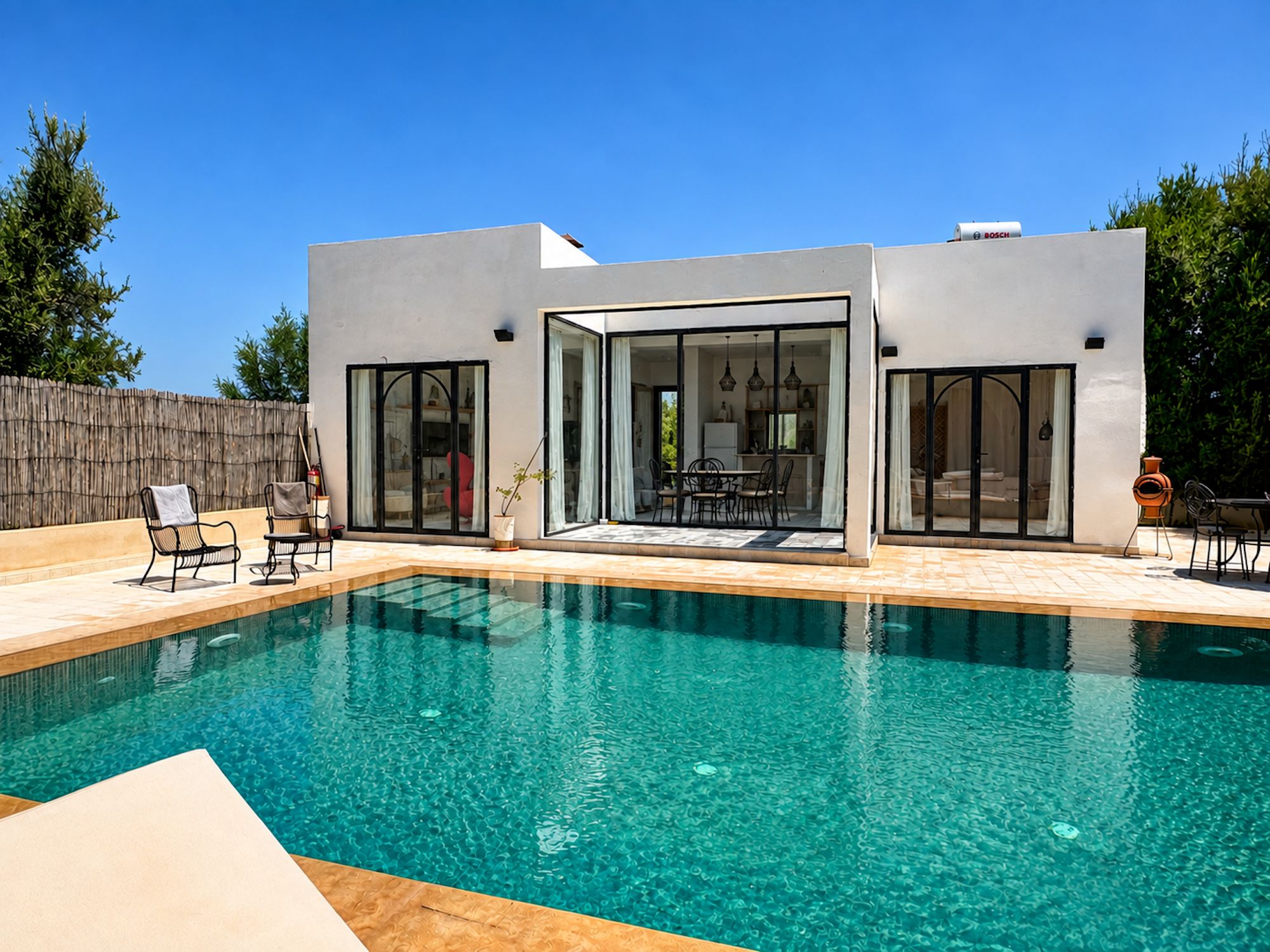 A modern house with a swimming pool, large glass doors, and outdoor furniture.