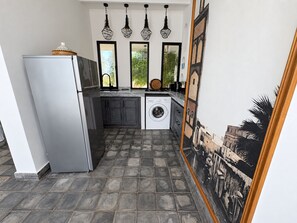 Eine kleine Küche mit Kühlschrank, Waschmaschine und Spüle.