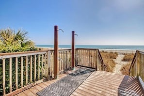 Eine Holzterrasse führt zu einem Strand mit freiem Blick auf den Ozean.