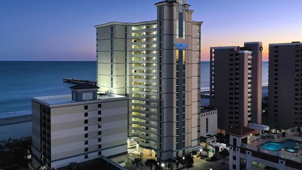 A high-rise hotel with multiple floors, a pool area, and a view of the ocean. - Oceanview 1BR Suite + Lazy River & Hot Tub (Myrtle Beach)