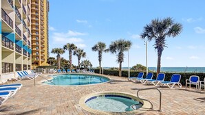 A pool area with lounge chairs, a hot tub, and palm trees. - Oceanview 1BR Suite + Lazy River & Hot Tub (Myrtle Beach)