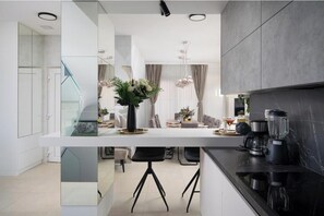 A modern kitchen with a central island, black appliances, and a glass partition. - Villa Isla Verde (Medulin)
