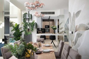A modern dining area with a wooden table, chairs, and a chandelier. - Villa Isla Verde (Medulin)