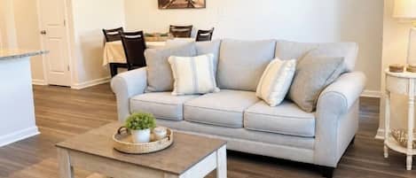 Una sala de estar con sofá, una mesa de centro y un comedor con sillas y una mesa.