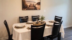Uma mesa de jantar posta com pratos, copos e um arranjo central.