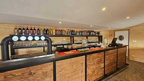 A bar area with a counter, shelves of bottles, and a coffee machine.