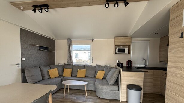 A compact living space with a sofa, a dining table, a kitchen area, and a window providing natural light.