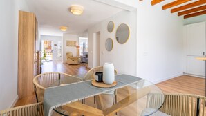 Un comedor moderno con una mesa de vidrio, sillas de mimbre y techo de madera.