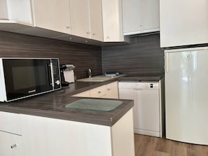 Eine moderne Küche mit Mikrowelle, Kaffeemaschine, Geschirrspüler und Kühlschrank.