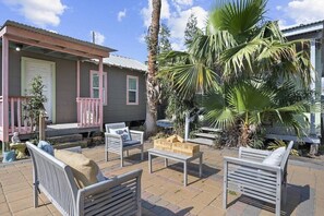 Un patio con mobiliario exterior, una mesita y una palmera.