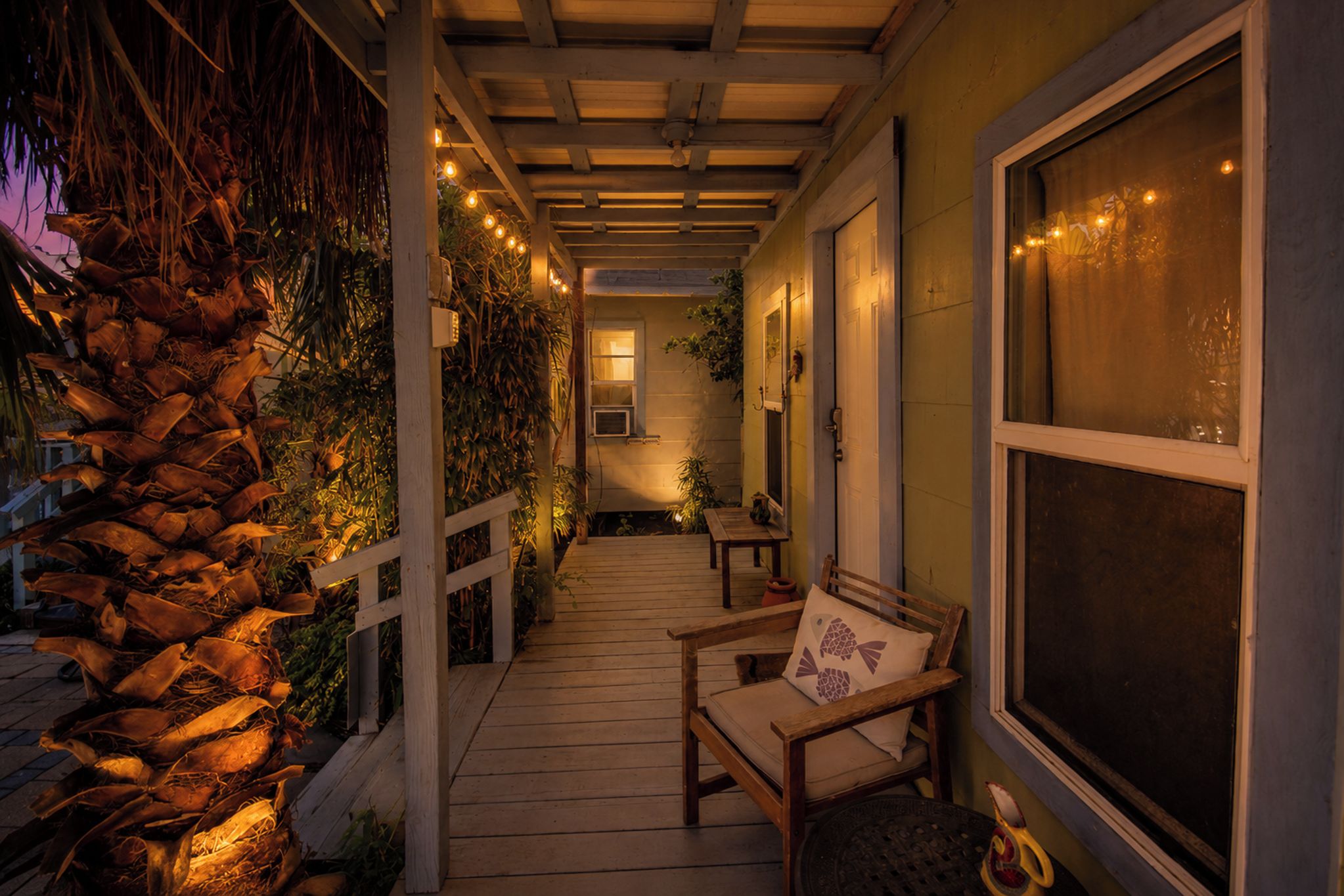 A covered outdoor area with a wooden bench, a stone wall, and string lights.