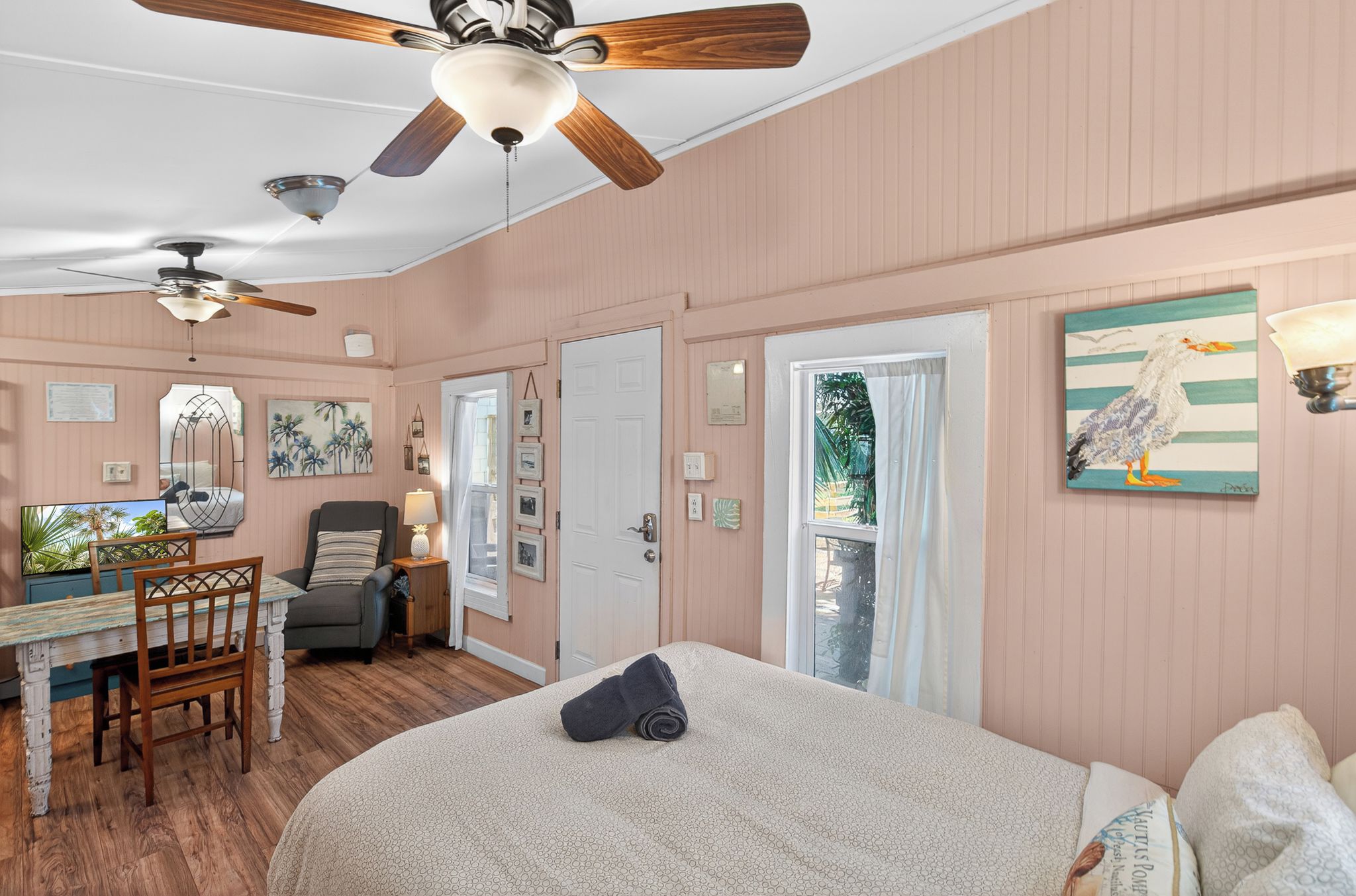 A bedroom with a bed, a desk, a chair, and a ceiling fan.