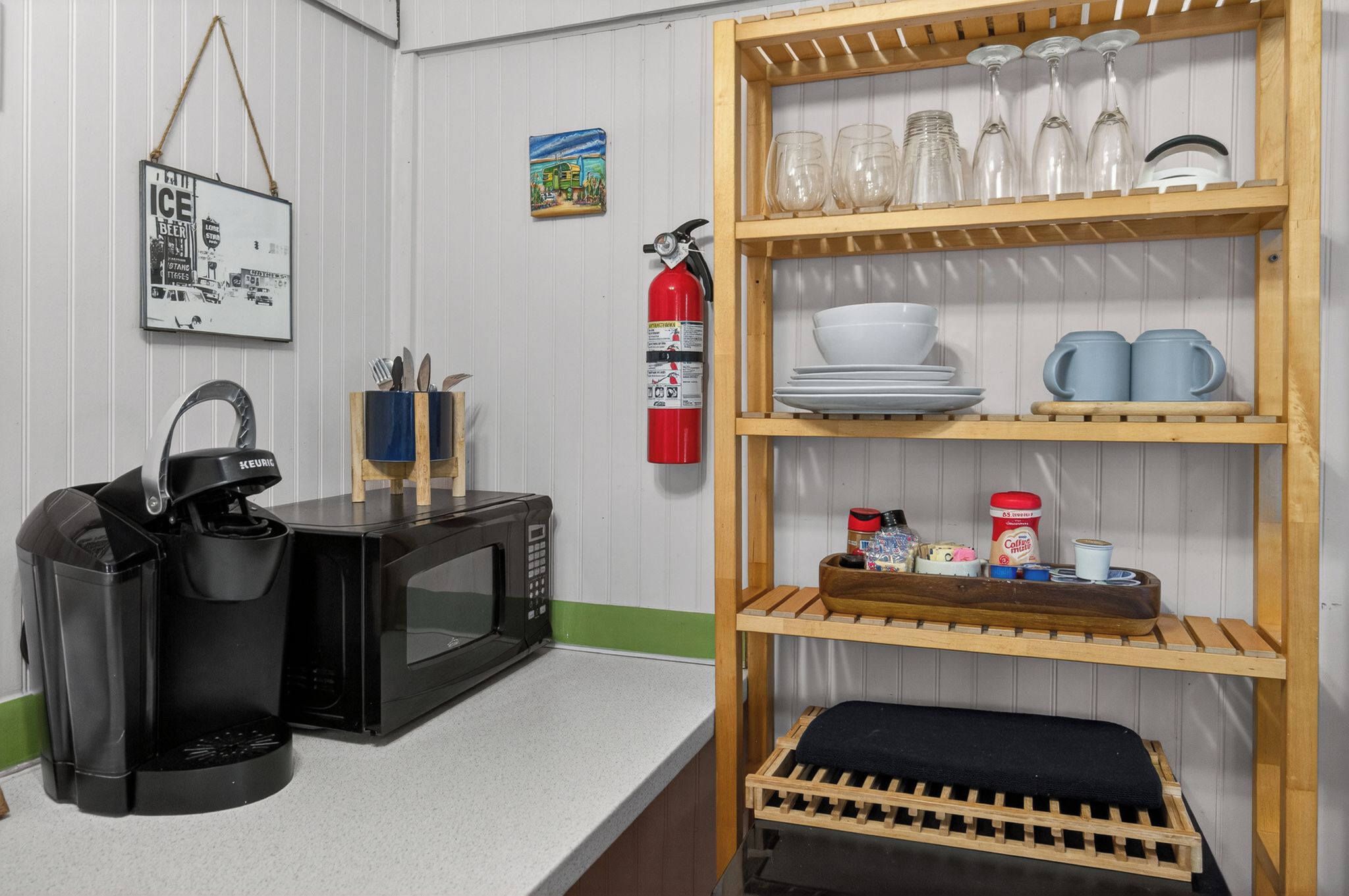 A kitchen with a coffee maker, microwave, and shelves with glassware and dishes.