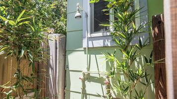 A green house with a window, a wooden fence, and a bamboo plant.