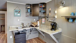 Una cocina compacta con un lavamanos integrado, una cafetera y una pequeña encimera.