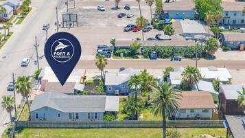 Luchtbeeld van een woonwijk met huizen, palmbomen en een parkeerplaats.