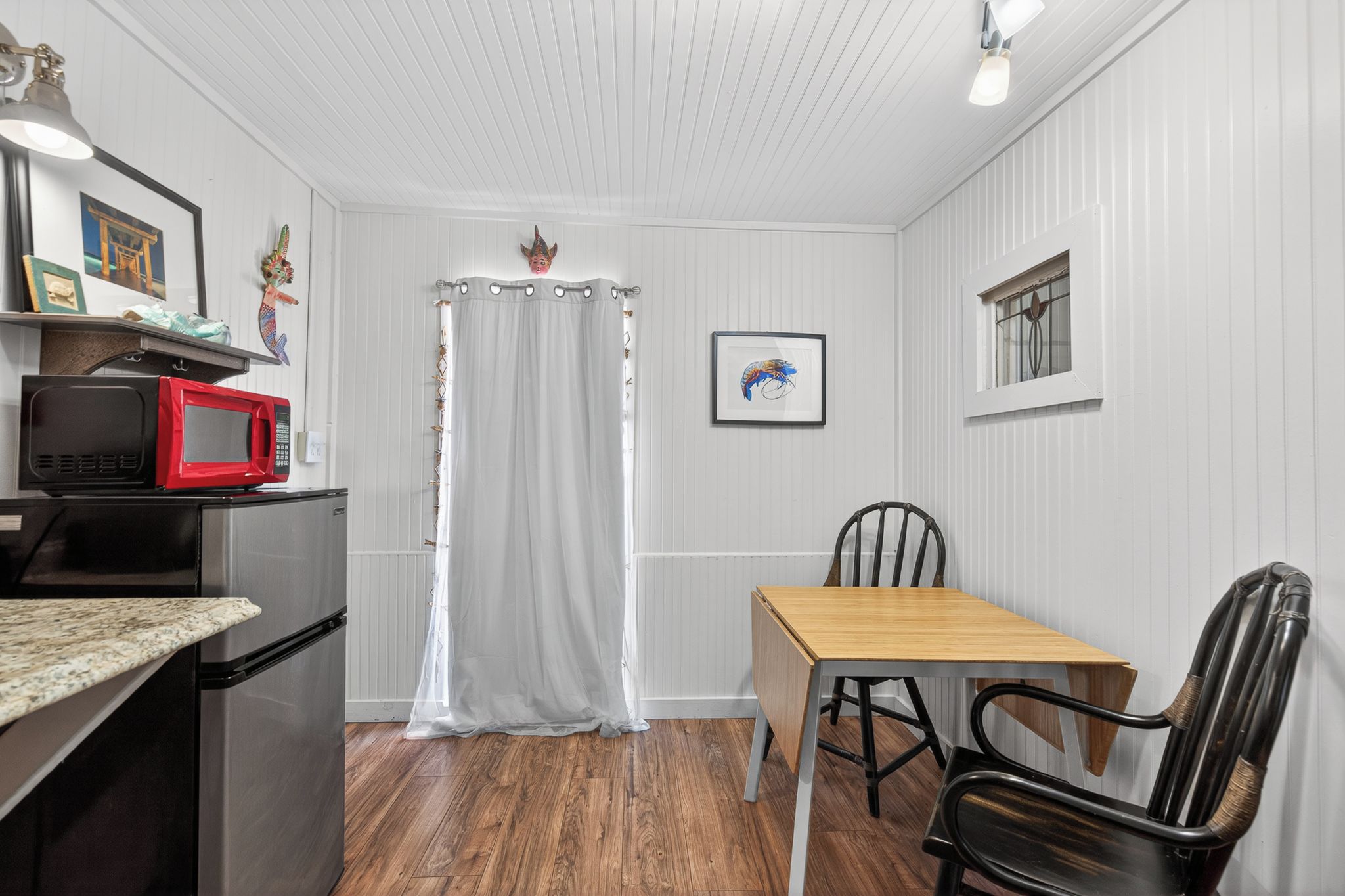 A compact kitchen with a refrigerator, microwave, and a dining area with a table and chairs.