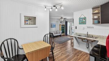 A compact kitchen with a wooden table and chairs, a built-in sink, and a ceiling fan.