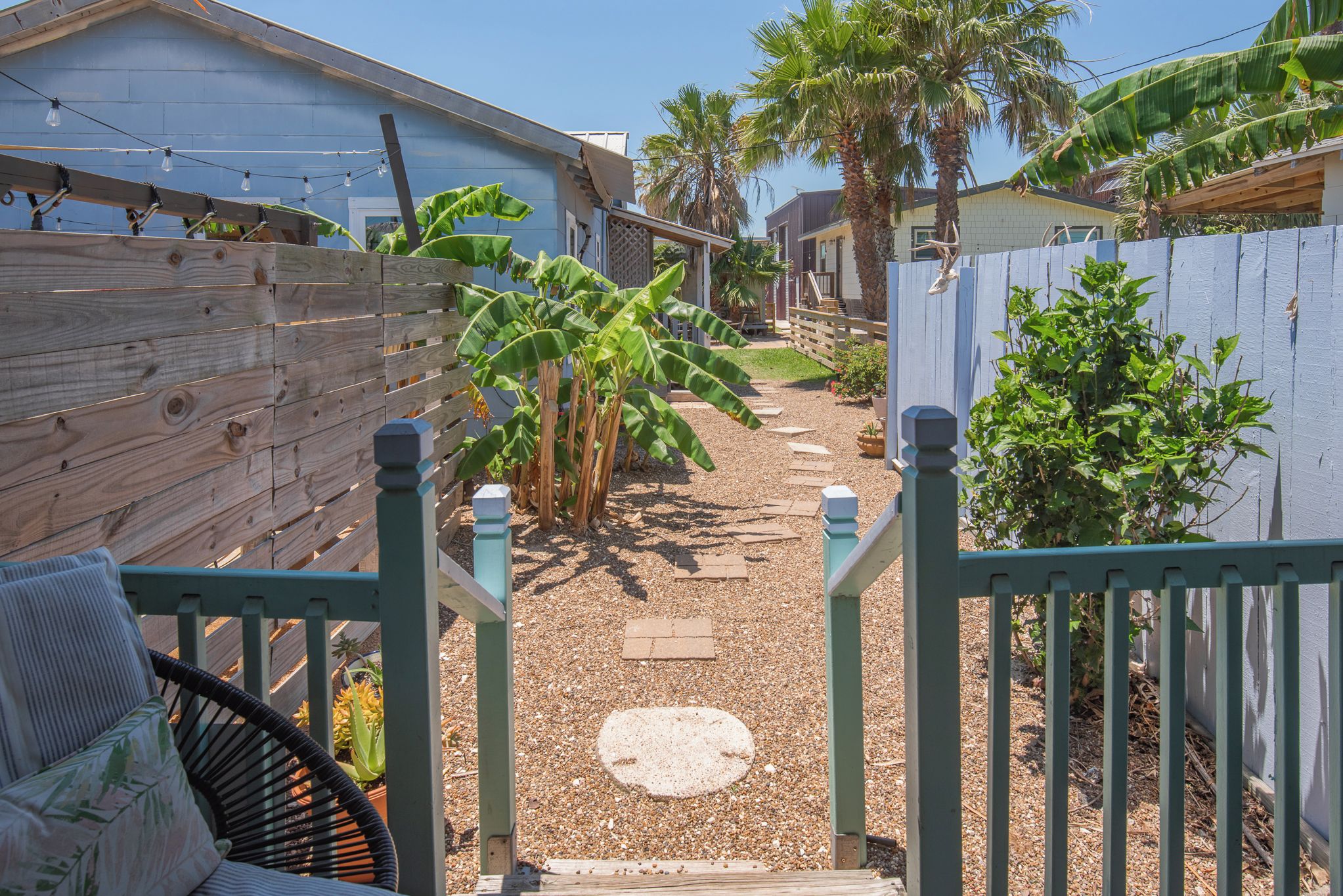 A backyard with a wooden fence, a chair, and a pathway leading to a house.
