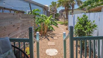 A backyard with a wooden fence, a chair, and a pathway leading to a house.