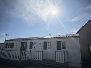 Een laag gebouw met een puntige dakschild, een veranda met een leuning en een kleine voordeur.