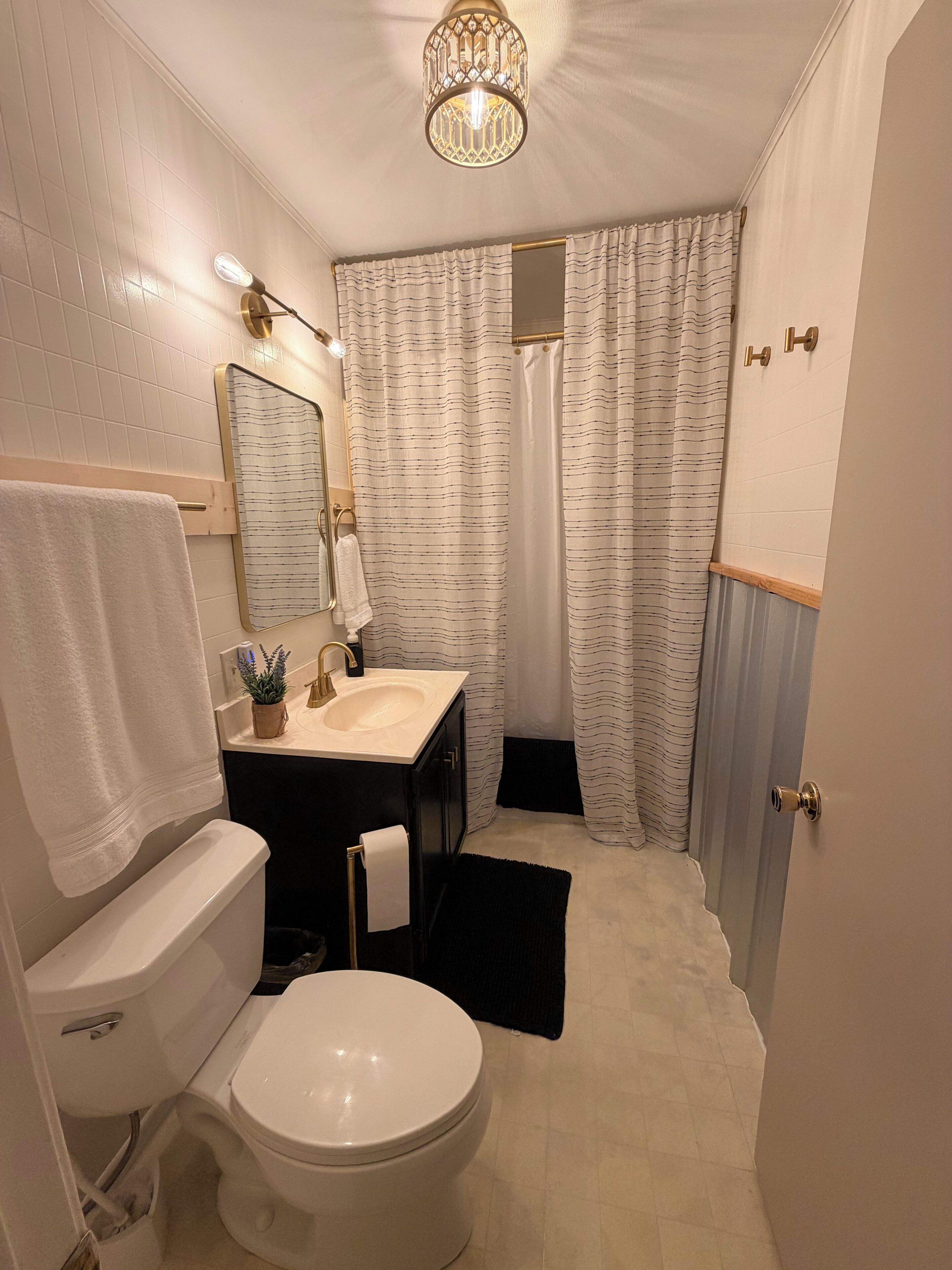 A bathroom with a toilet, sink, mirror, and shower curtain.