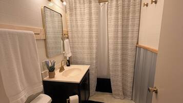 A bathroom with a toilet, sink, mirror, and shower curtain.