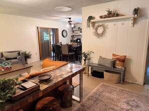 Ein Wohnzimmer mit Essbereich, Kamin und einer Küche im Hintergrund.