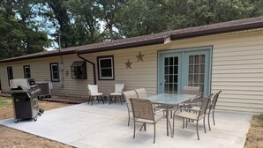 A patio with a grill, outdoor furniture, and a building with a star decoration. - Cozy Cottage on 9 tranquil acres in Wright City, Mo. Minutes to wedding venues! (Wright City)