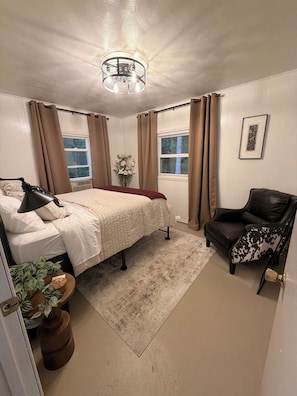 Ein Schlafzimmer mit Bett, Stuhl, Fenster und Deckenleuchte.