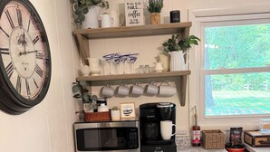 A kitchen with dark cabinets, a microwave, a coffee maker, and a clock on the wall. - Cozy Cottage on 9 tranquil acres in Wright City, Mo. Minutes to wedding venues! (Wright City)