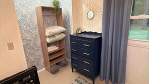 A room with a patterned wall, a blue dresser, a rug, and a window with curtains. - Cozy Cottage on 9 tranquil acres in Wright City, Mo. Minutes to wedding venues! (Wright City)