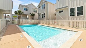 Una piscina rectangular con una cerca blanca, rodeada de edificios de varios pisos con balcones.
