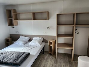 Ein Schlafzimmer mit einem Bett, Holzregalen und einem kleinen Nachttisch.