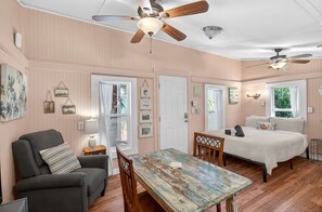 Ein Zimmer mit einem Bett, einem Schlafsofa, einem Tisch und zwei Deckenventilatoren.