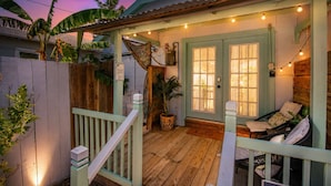 Uma casa com varanda, cerca de madeira e um banco.