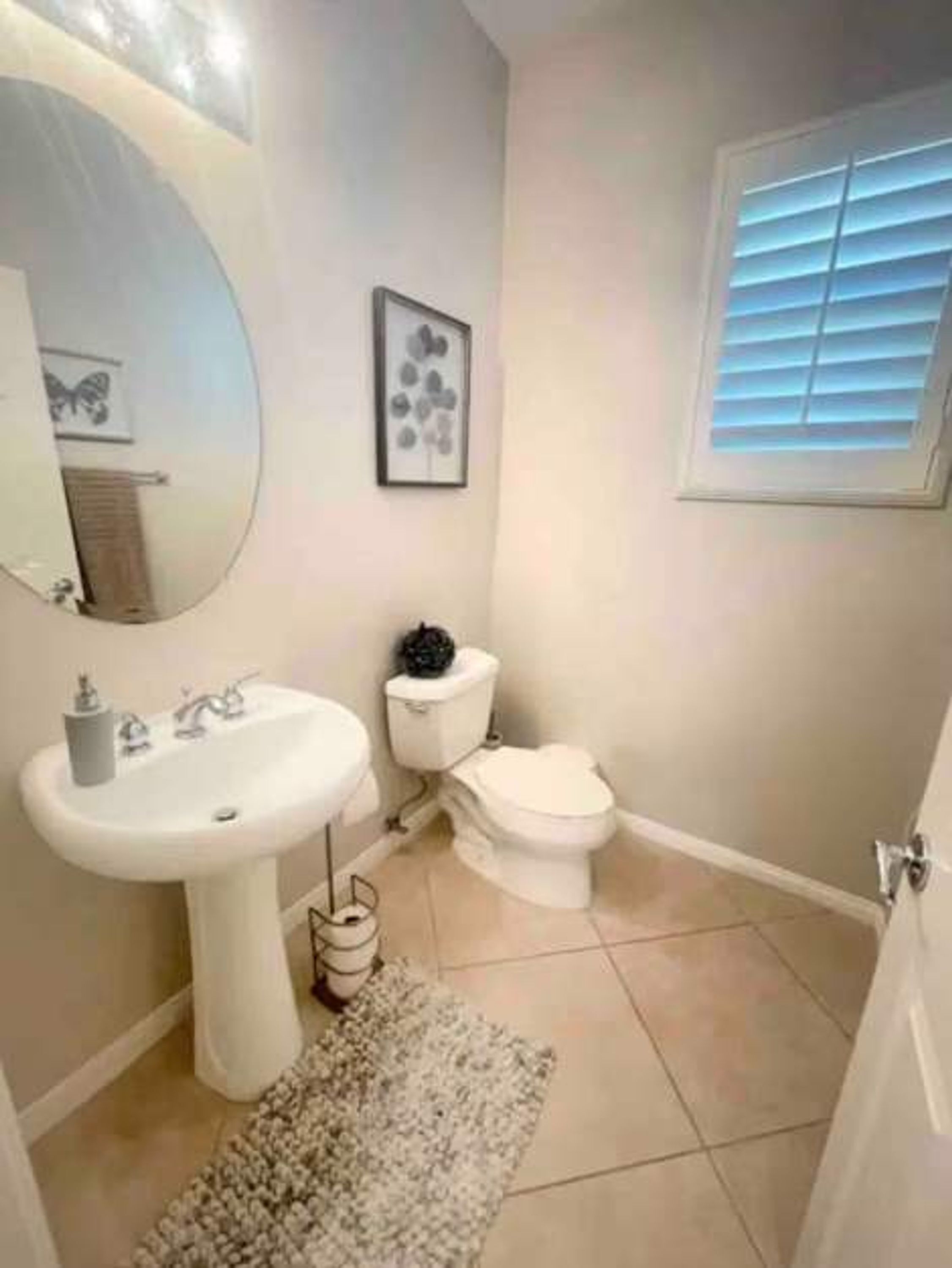 A bathroom with a sink, toilet, and a window with blinds.