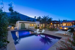 A pool with lounge chairs, a patio area, and a building with a mountain backdrop. - Private Oasis Retreat (Palm Springs)