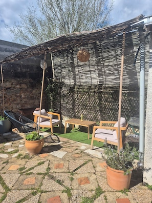 Un patio con una mesa y sillas, un colgante de luz y un poste de bambú.