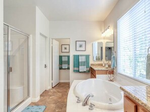 A bathroom with a large bathtub, a shower, and a vanity with a mirror. - Pools Golf and Tennis Home (Indio)
