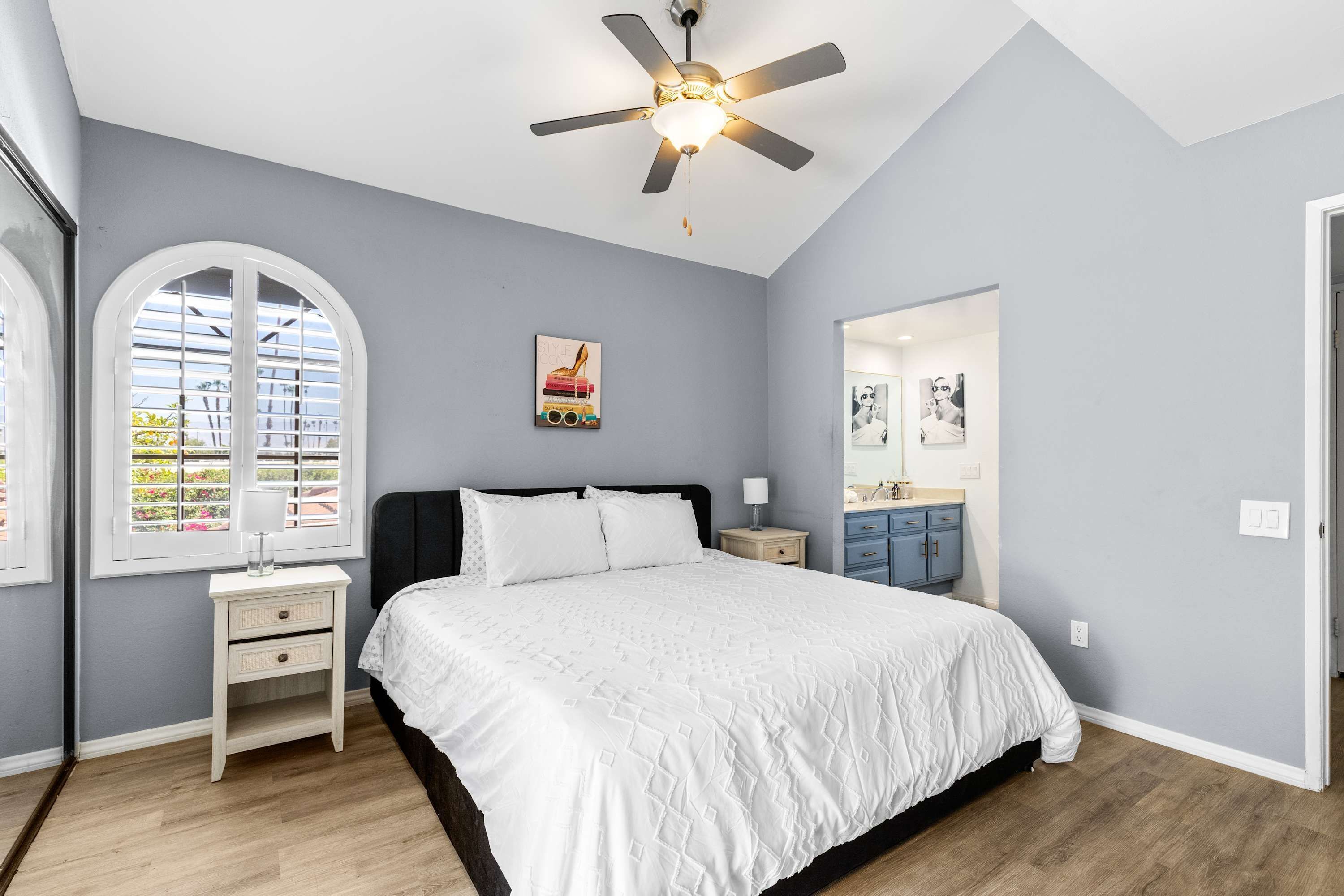 A bedroom with a bed, a ceiling fan, a nightstand, a dresser, and a window with blinds.