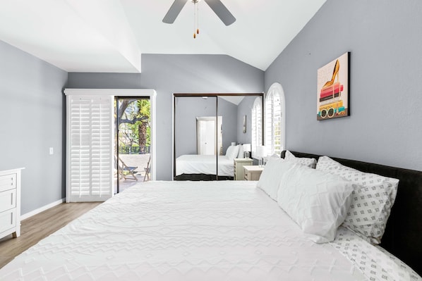 A bedroom with a bed, a nightstand, a dresser, and a window with blinds. - South Cherokee in Palm Springs (Palm Springs)