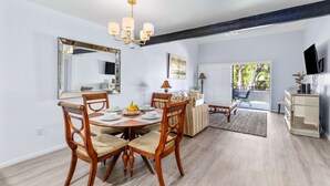 A dining area with a wooden table and chairs, a chandelier, and a large mirror on the wall. - South Cherokee in Palm Springs (Palm Springs)